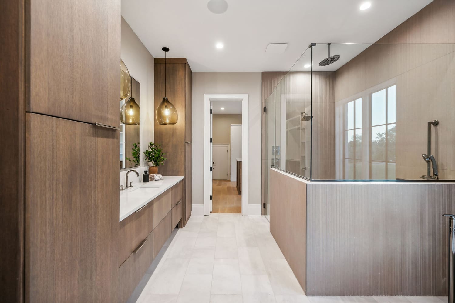 Modern bathroom with wood cabinets, white countertop, glass-enclosed shower, and beige walls.