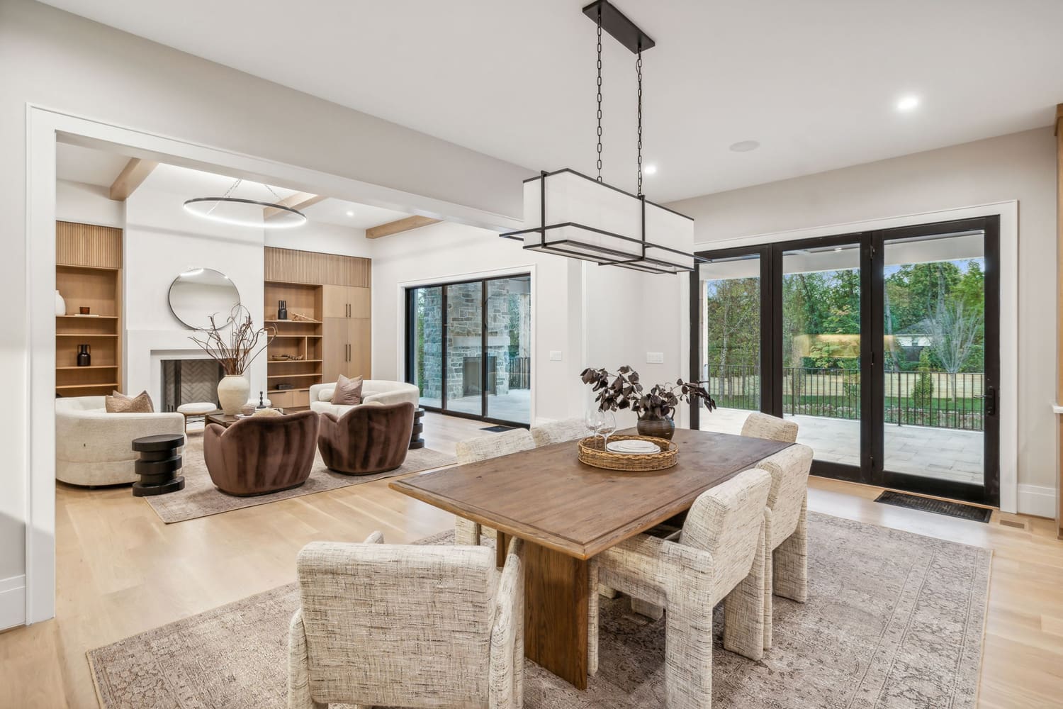 Open-concept dining and living area with wood flooring, fireplace, and large glass doors.