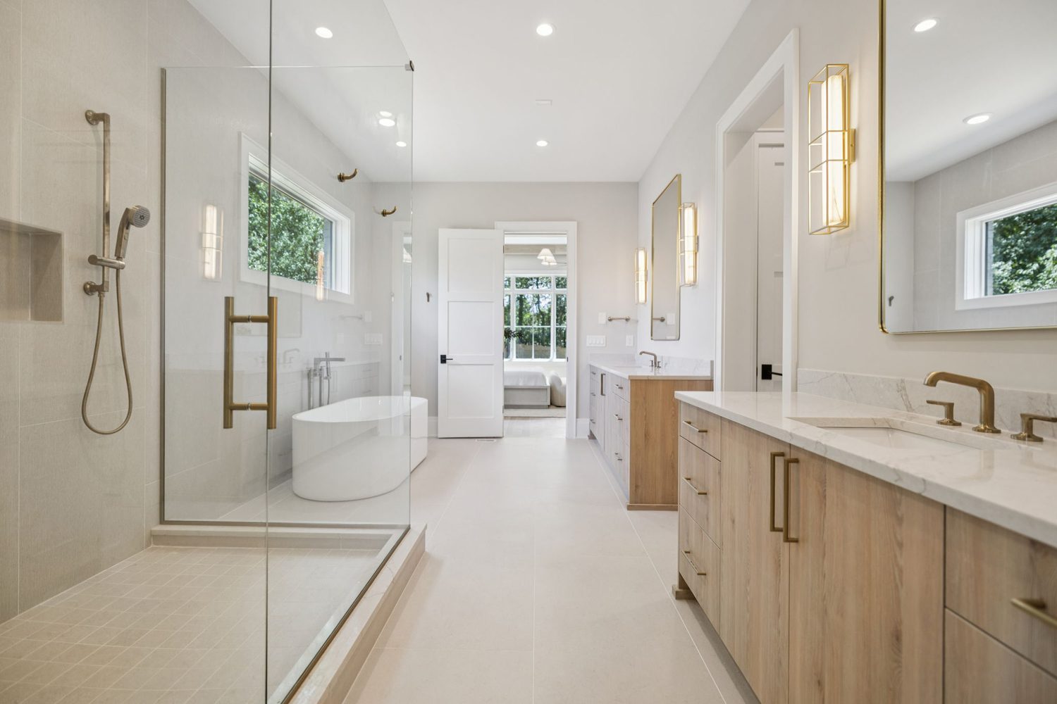 Modern bathroom with glass walk-in shower, freestanding tub, dual vanities, and large window.